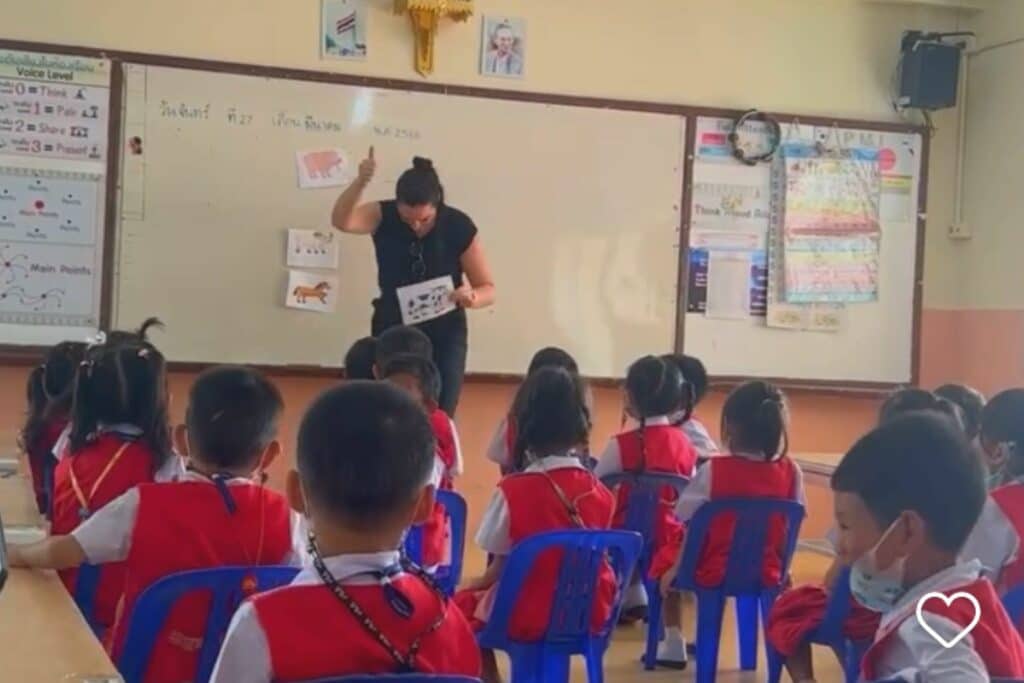 Female English teacher with small Thai students wearing red uniforms