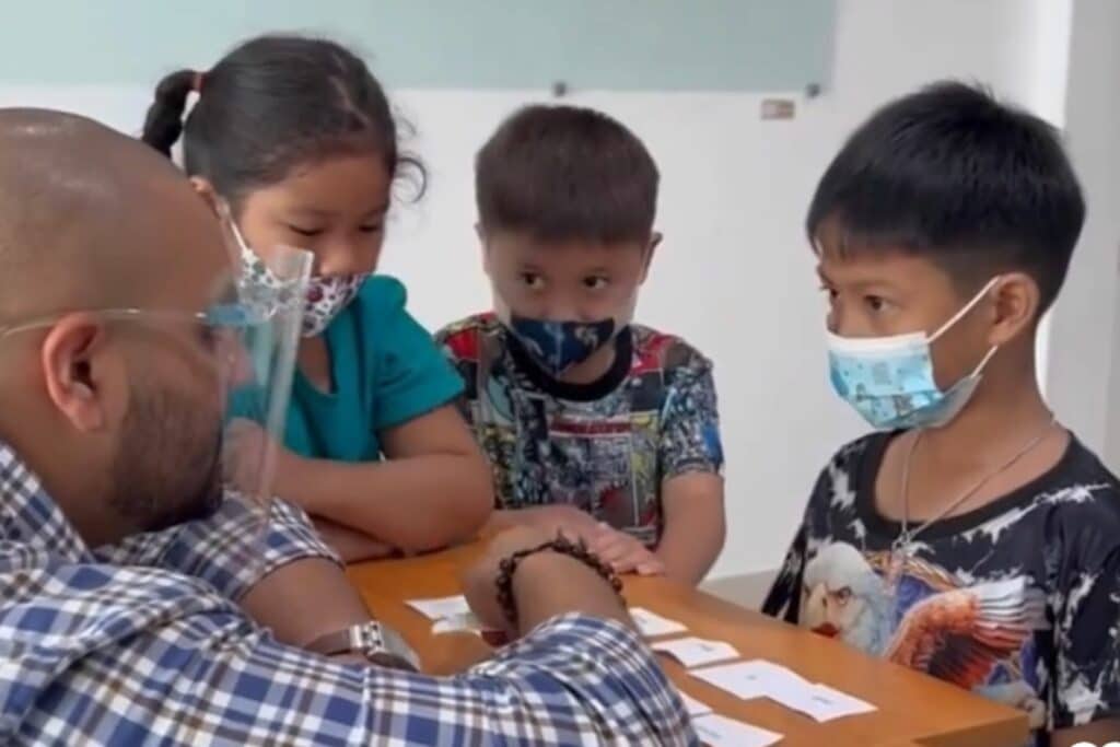 Male teacher talking to small Thai kids