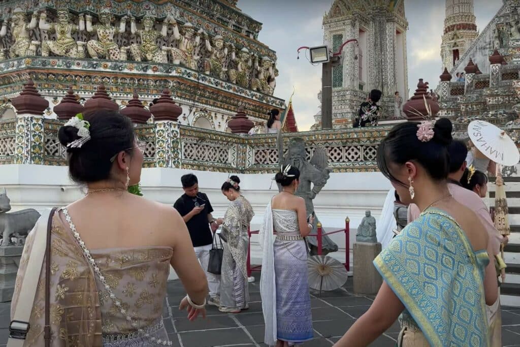 people dressed in traditional Thai clothing taking photos around the temple